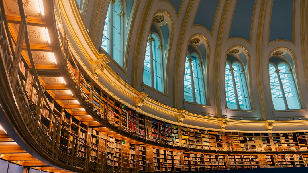 Historic library reading room with tall wooden bookshelves and warm light